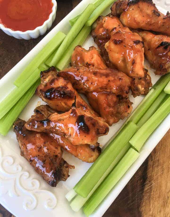 serving of celery and buffalo chicken wings on a white platter.
