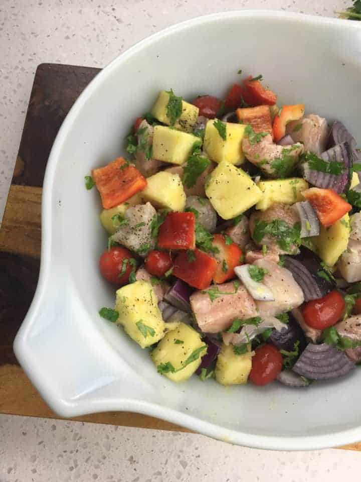 bowl of seasoned & mixed swordfish, pineapple, bell pepper, onion, and cilantro