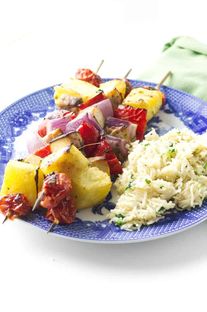 blue & white plate with three swordfish & pineapple kabobs and cilantro rice.