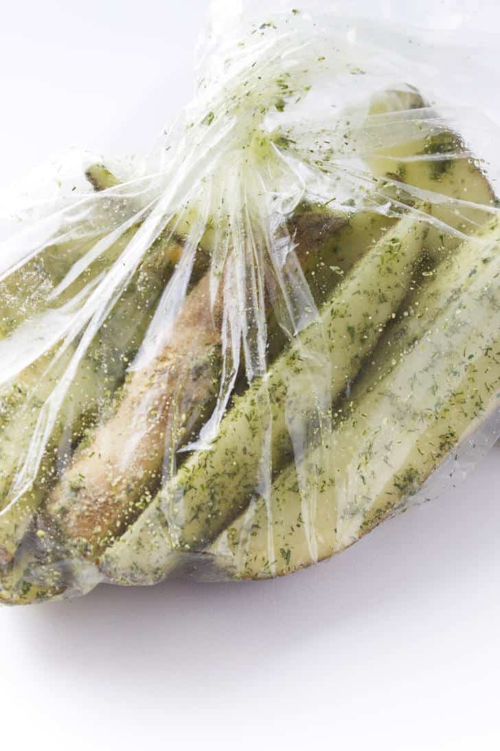 plastic bag with seasoning and raw potatoes.