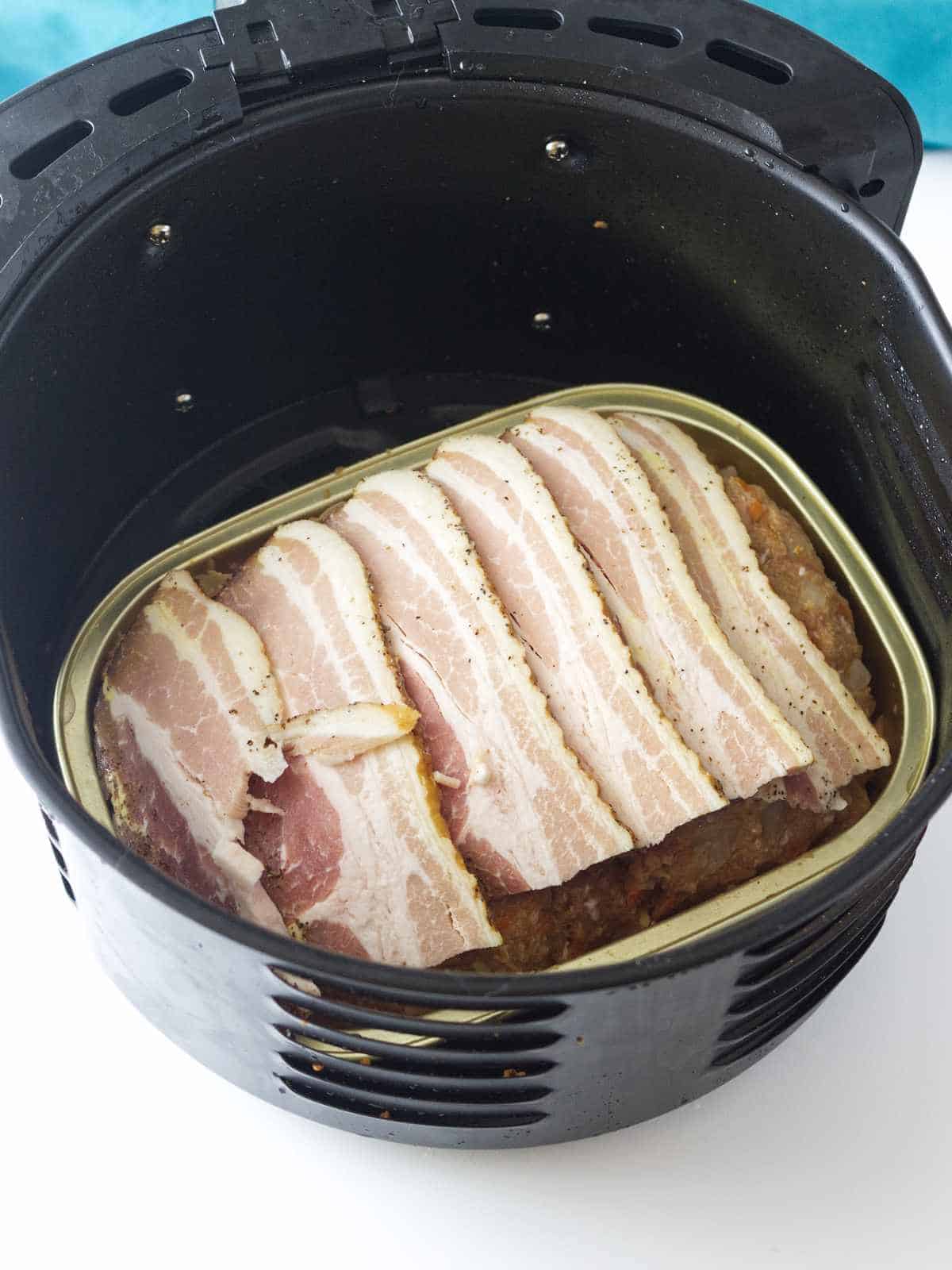 turkey meatloaf with bacon on top in a air fryer.