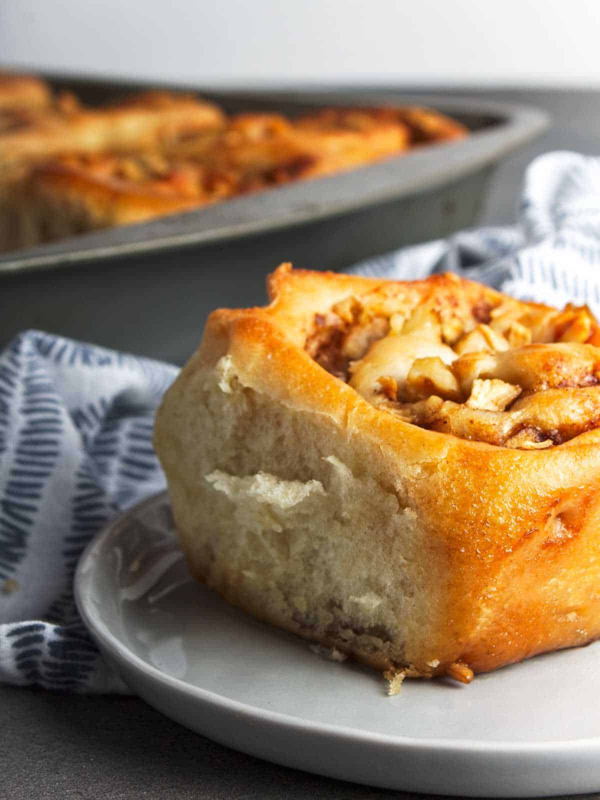 one cinnamon apple rolls on a serving plate.