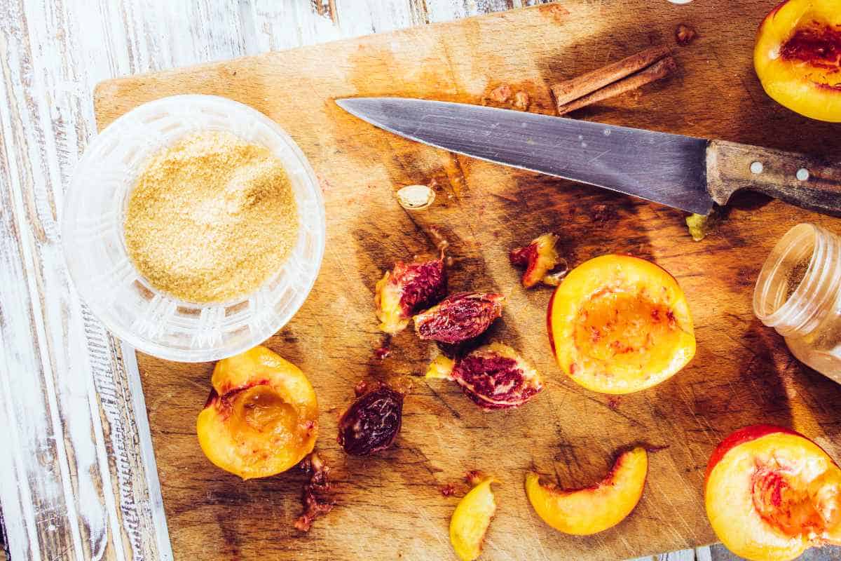 cutting board with halved, pitted stone fruit and a bowl of cinnamon.