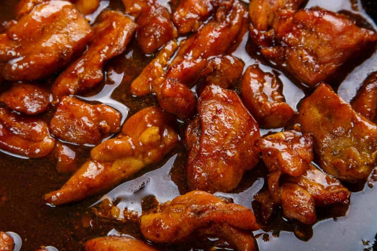 close up of bourbon chicken cubes and sauce cooking.