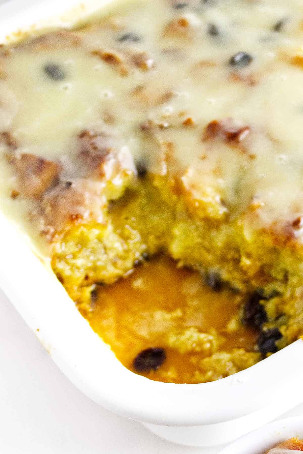 Rum Raisin bread pudding in a casserole dish with a serving removed.