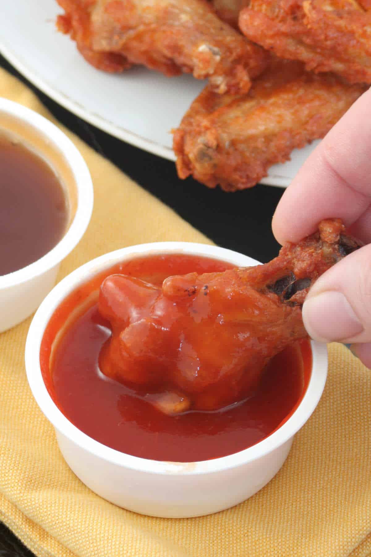 dipping a chicken wing into a spicy buffalo sauce.