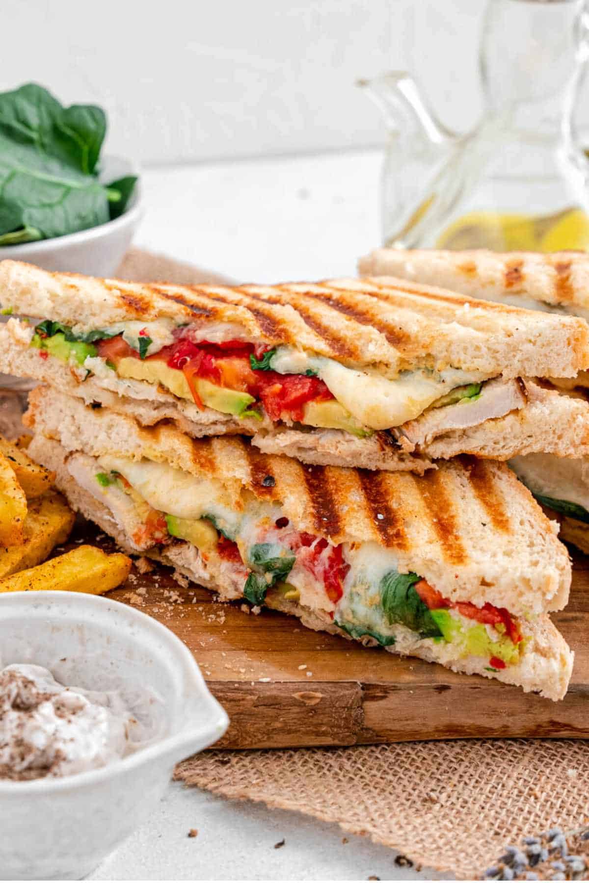Diagonally sliced grilled chicken avocado panini on a cutting board.