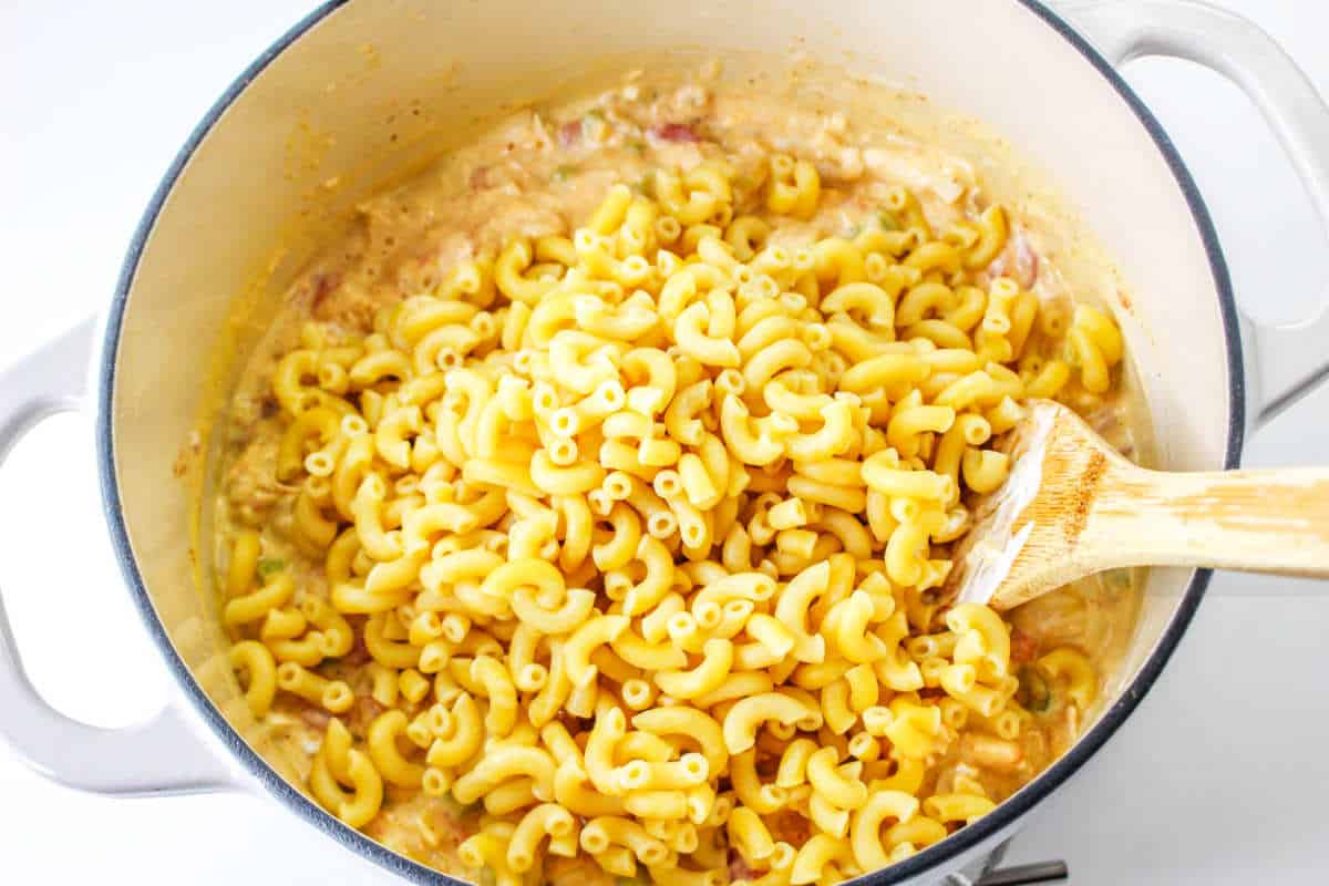 cooked elbow macaroni added to ingredients in a Dutch oven pot.