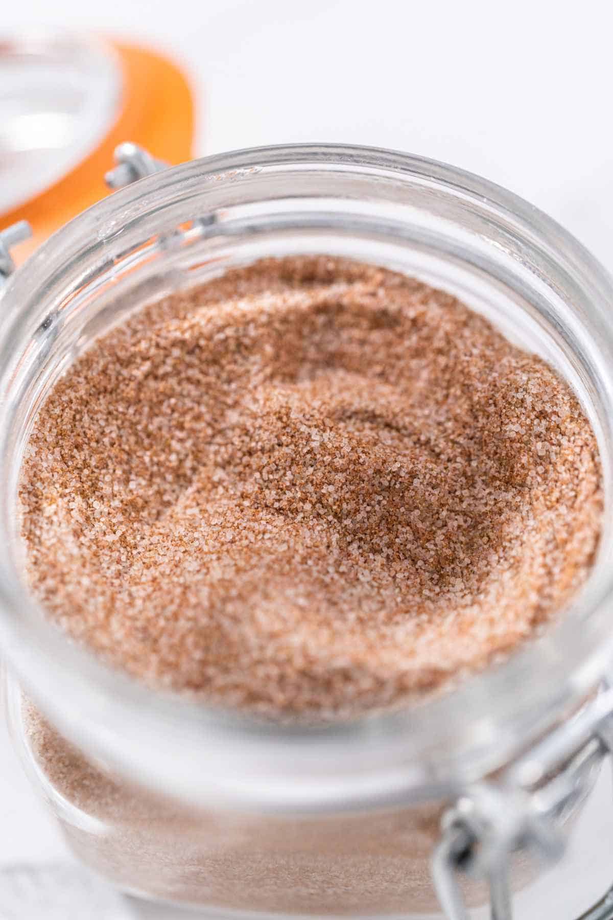 Cinnamon sugar in a glass mason jar on the marble surface.