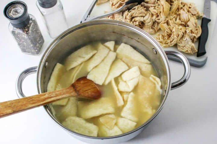 pastry strips cooking in broth in a large dutch oven.