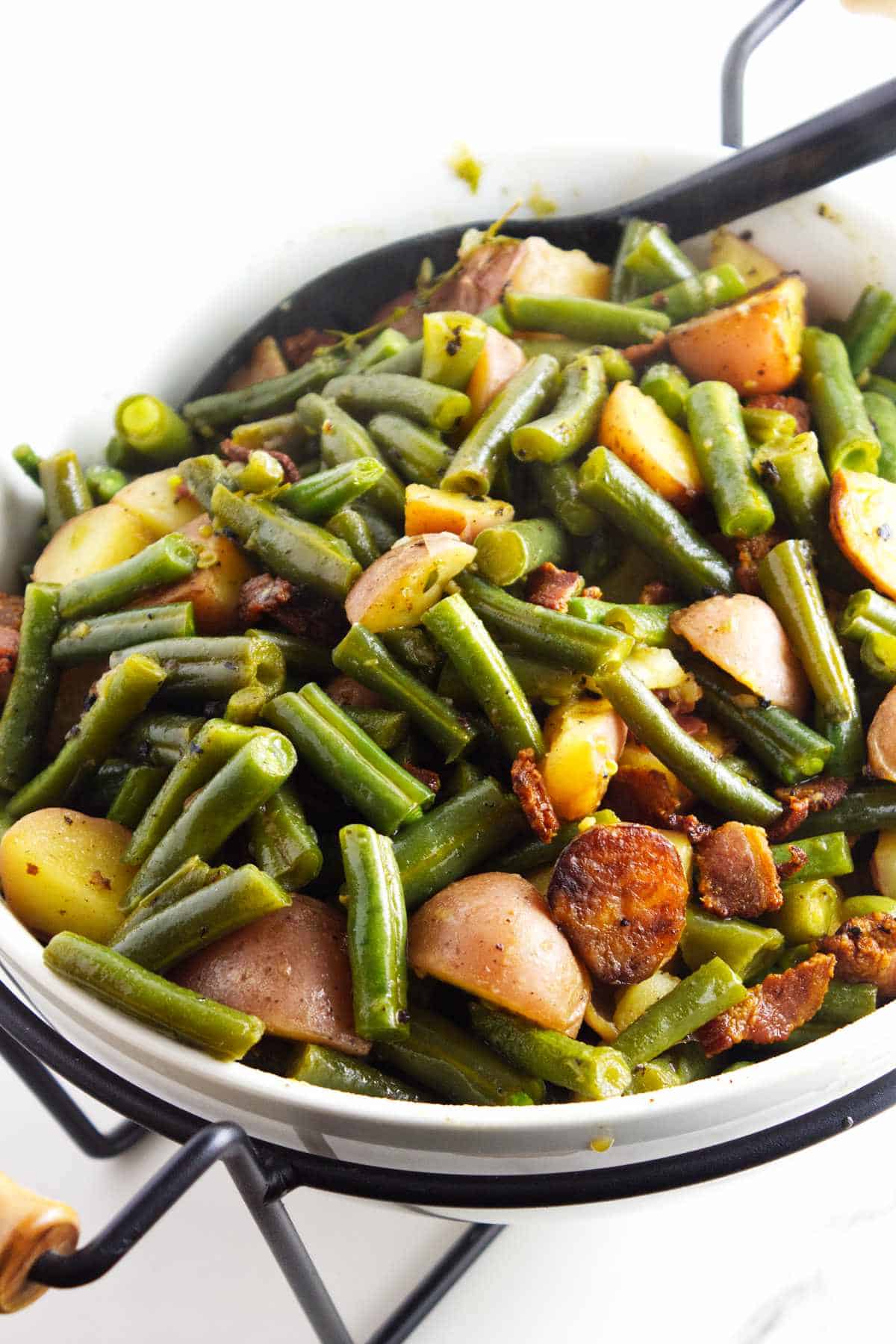 serving bowl with green beans, bacon, and potatoes.