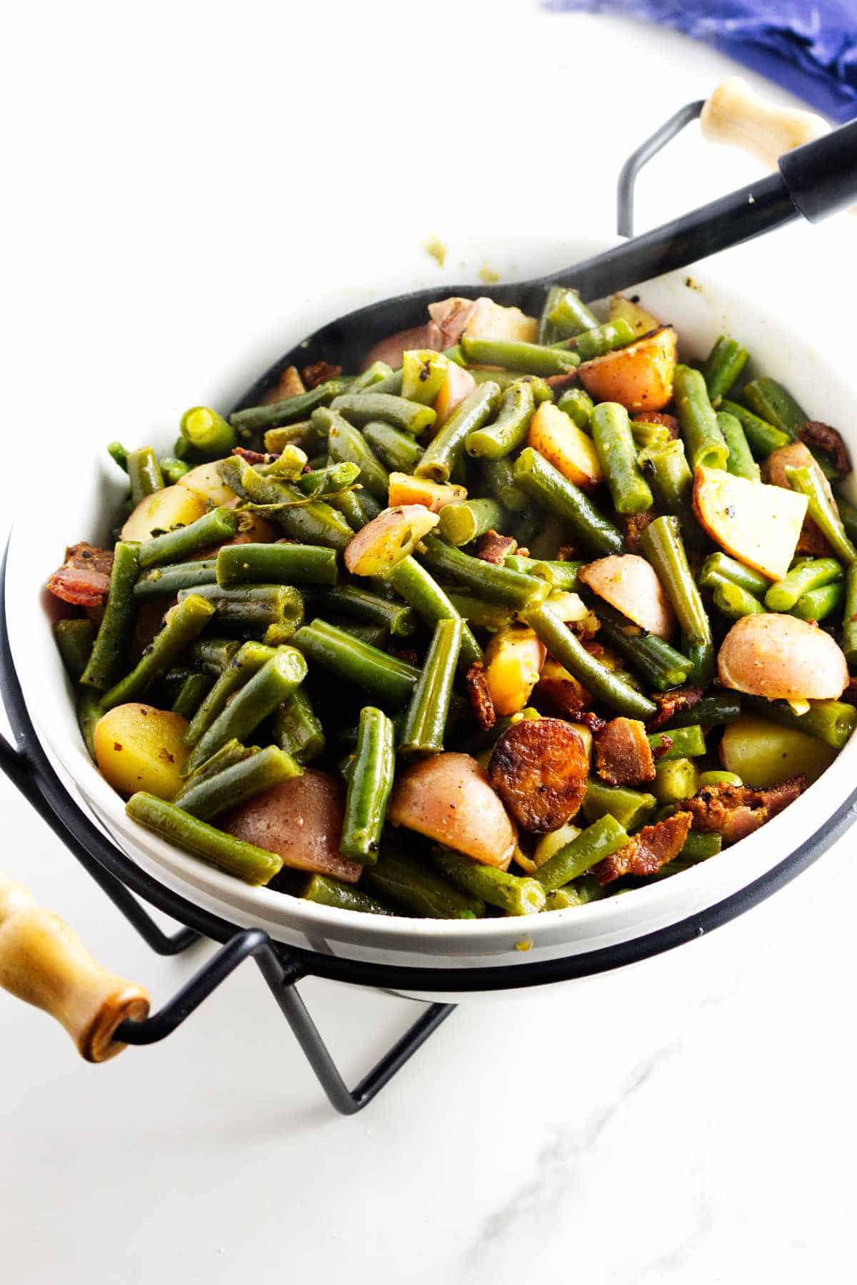 serving bowl with green beans, bacon, and potatoes.