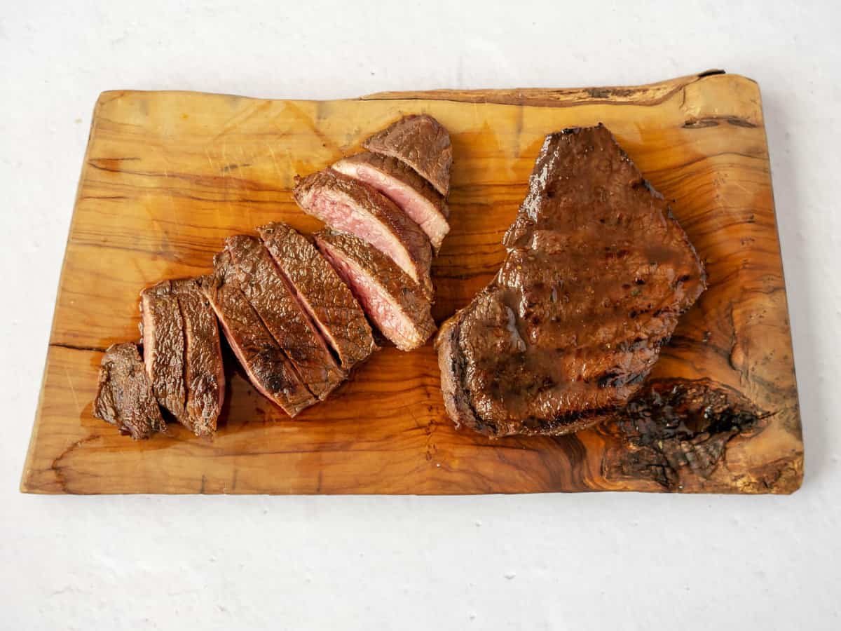 cutting board with steaks resting and sliced.