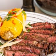 serving plate with corn on the cob and sliced beef.