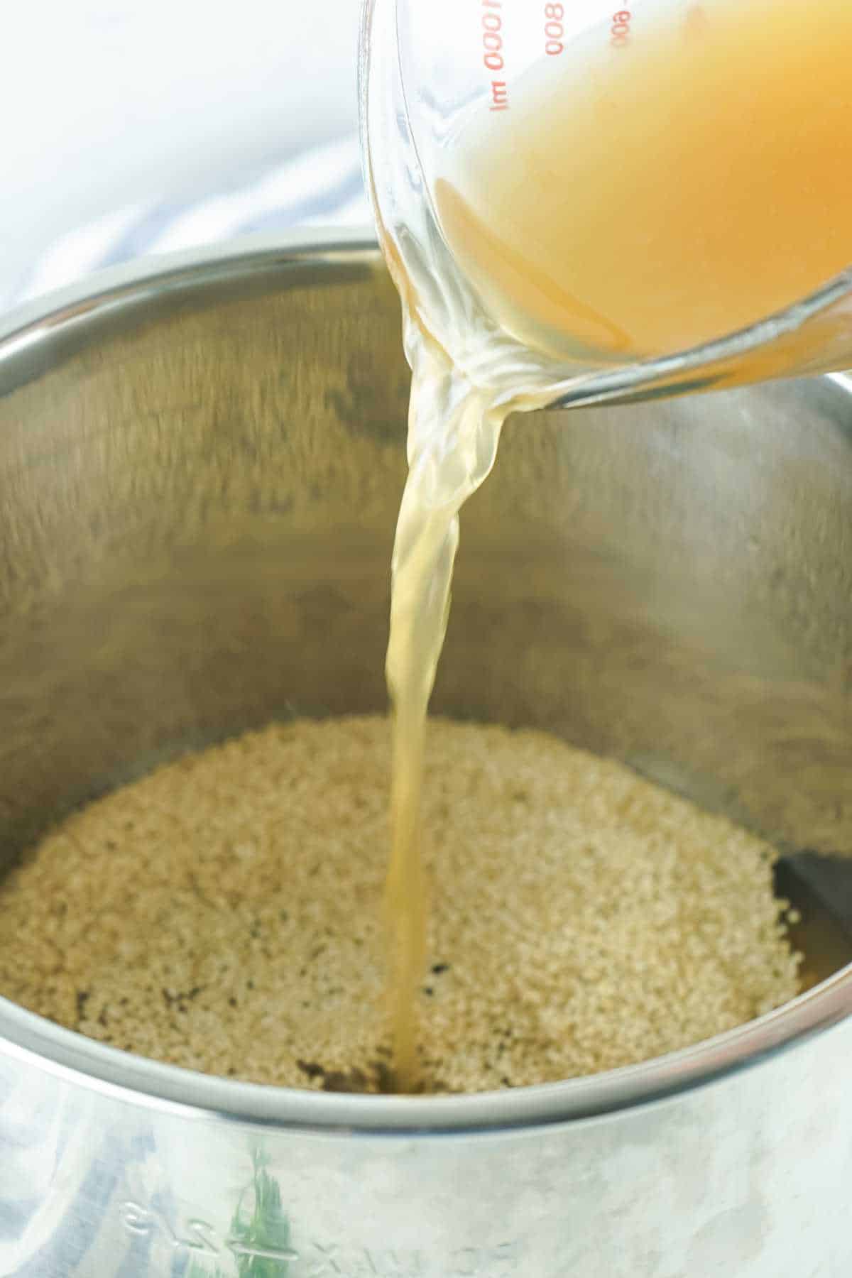 broth poured into a stainless pot with white grain.