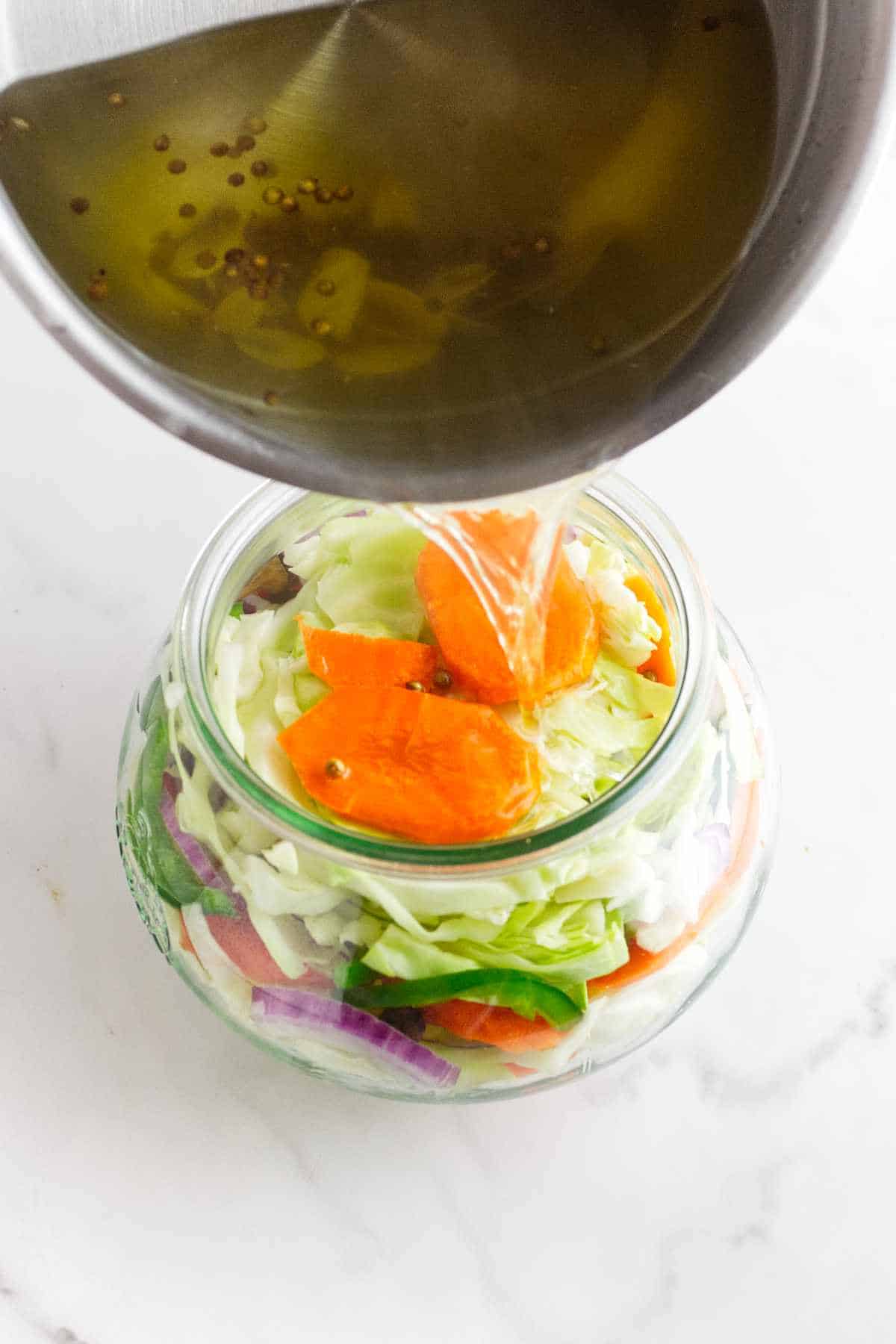hot pickling brine poured into jars of raw packed vegetables.