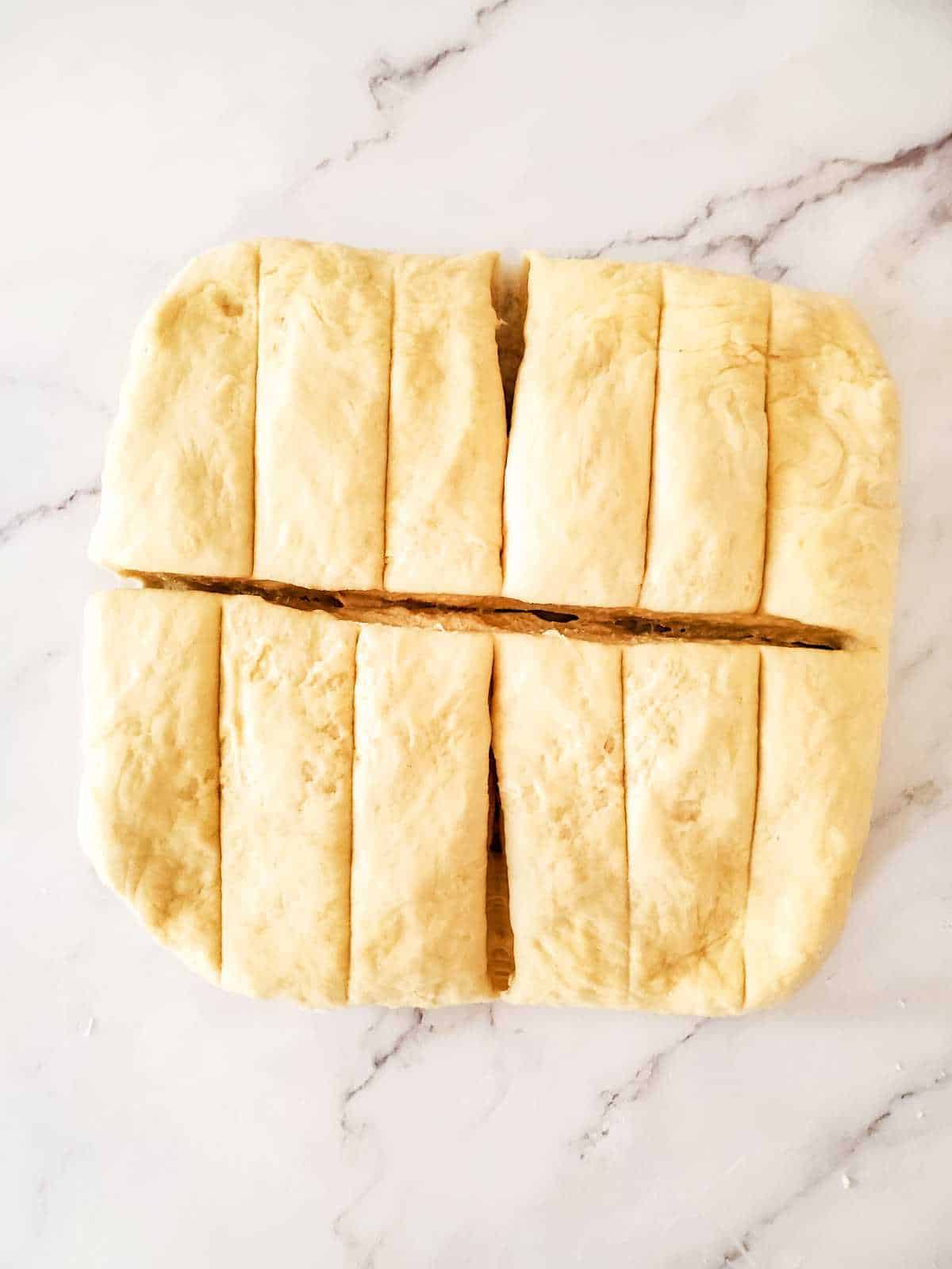 rectangle of homemade breadsticks dough cut into twelve pieces.