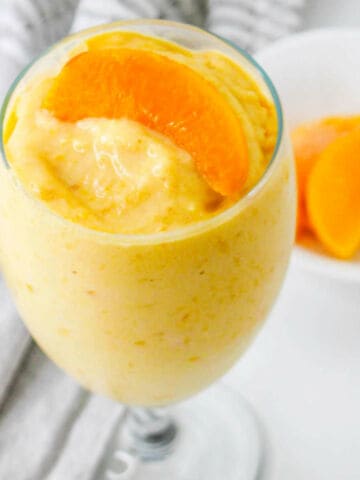 peaches and cream smoothie in a water goblet.