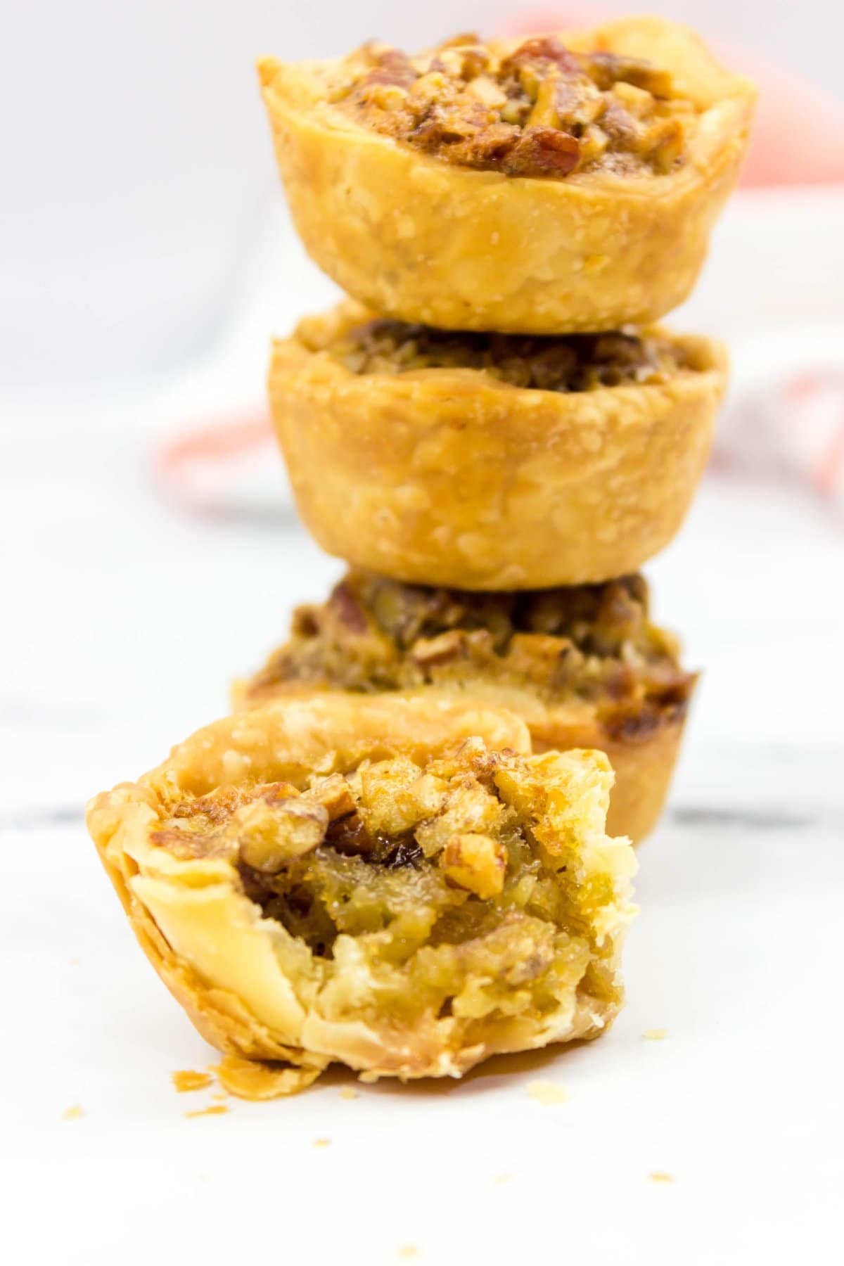 pampered chef pecan tassies stacked on a white background.