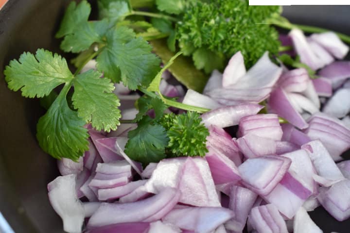 chopped red onion and cilantro on black cutting board.