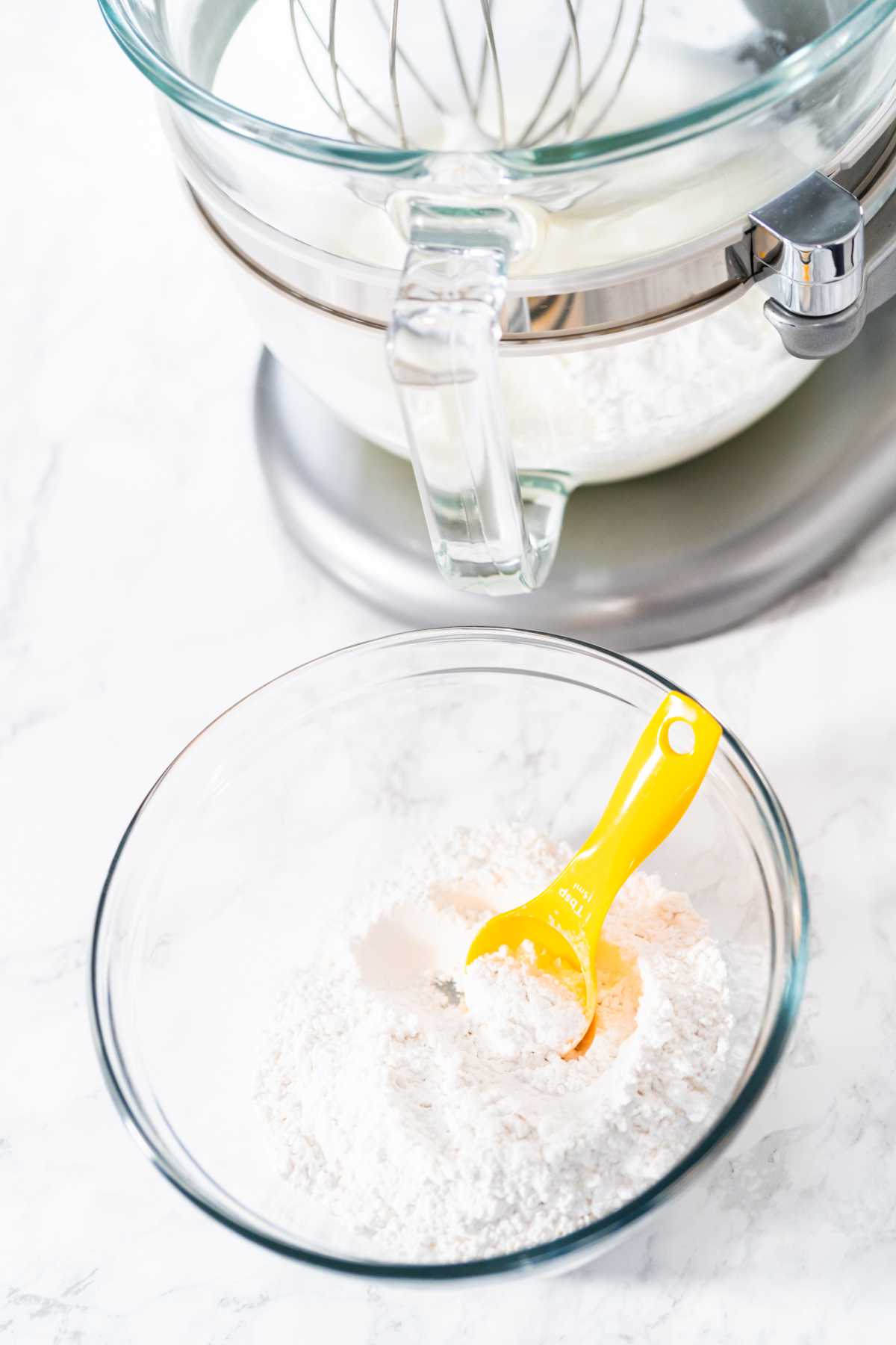 Adding powdered sugar to an kitchen electric with frothy egg whites.