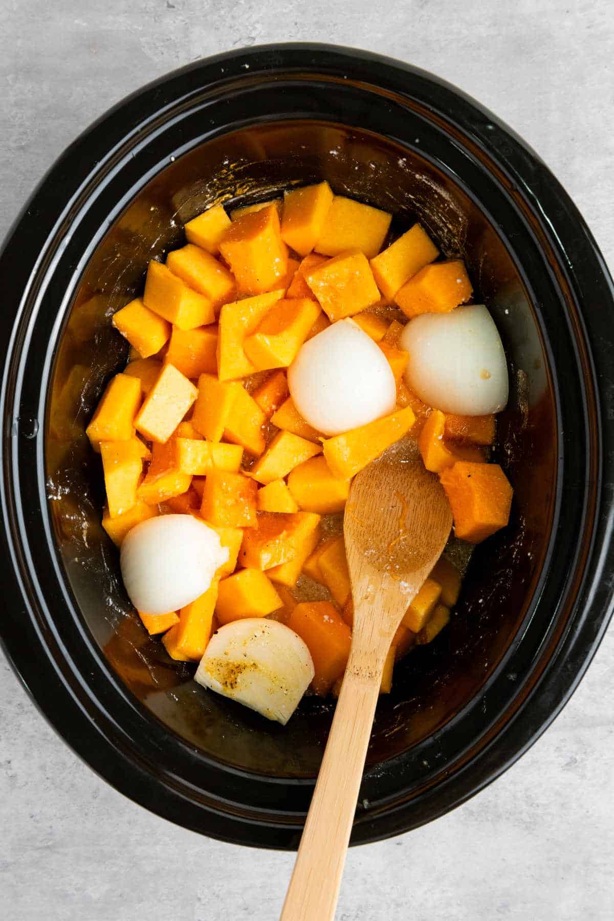 broth added to slow cooker with orange vegetables.