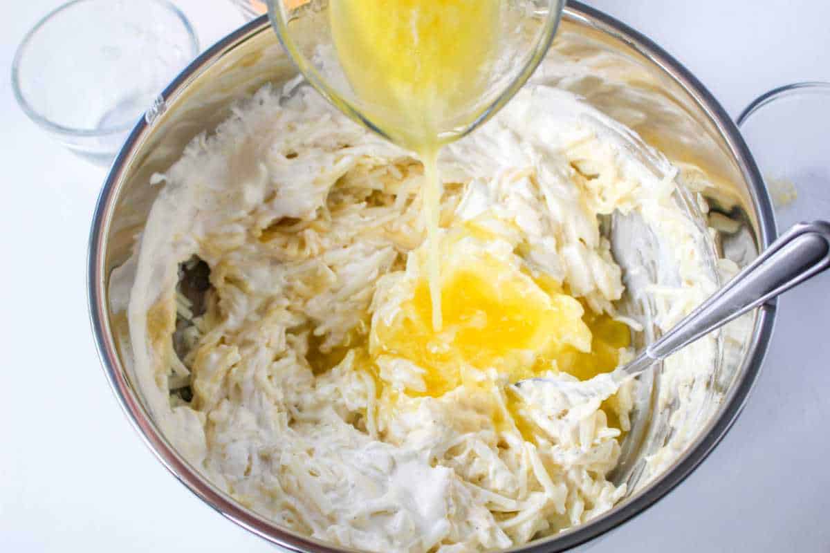 butter poured into mixing bowl on top of potatoes and sour cream.