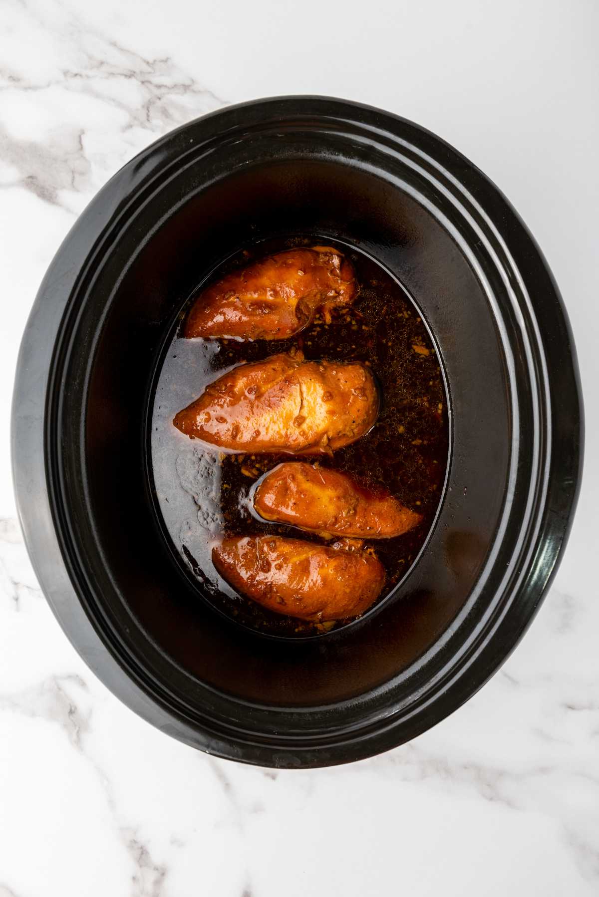 soy garlic sauce and chicken breasts cooking in a crockpot.