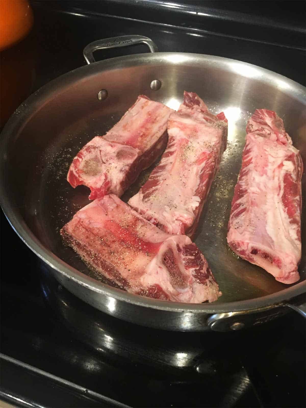 browning raw ribs in a skillet.