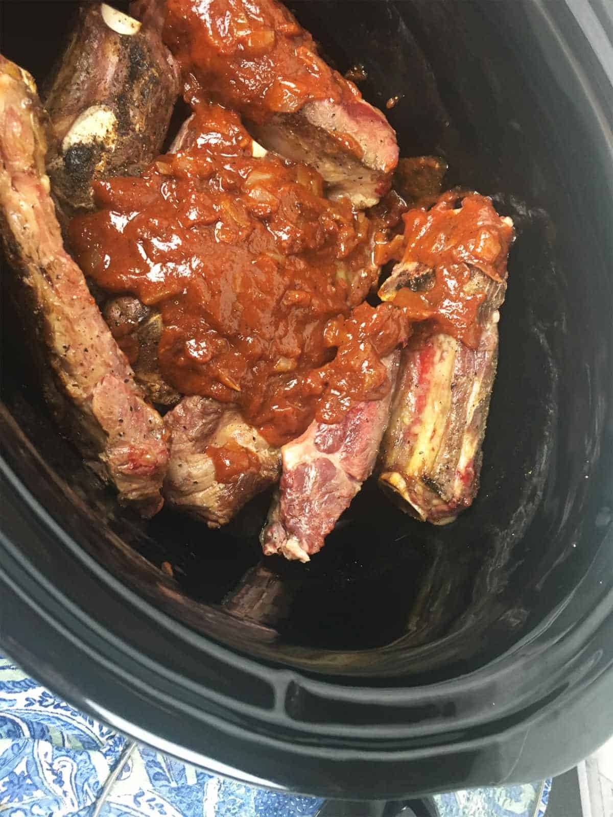 pan gravy added on top of beef back ribs in a crockpot.
