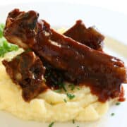 slow cooked beef back ribs on top of mashed potatoes on a plate.
