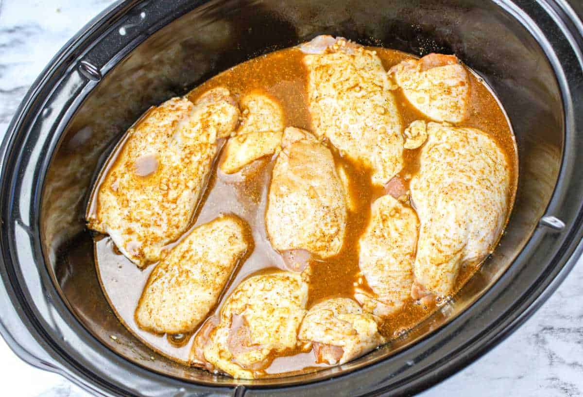 uncooked chicken thighs and seasoning mixture in a crockpot.