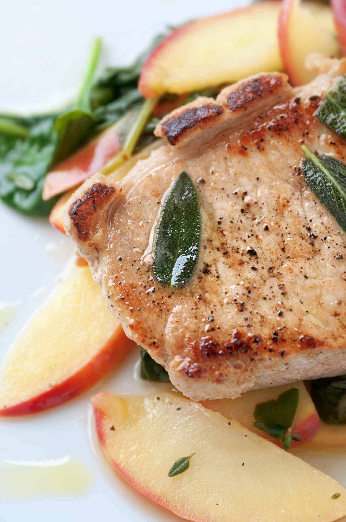 Golden brown pork chops with warm apple and sage leaves.