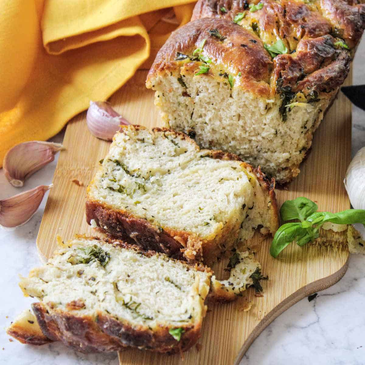 cut loaf of herb bread on cutting board.