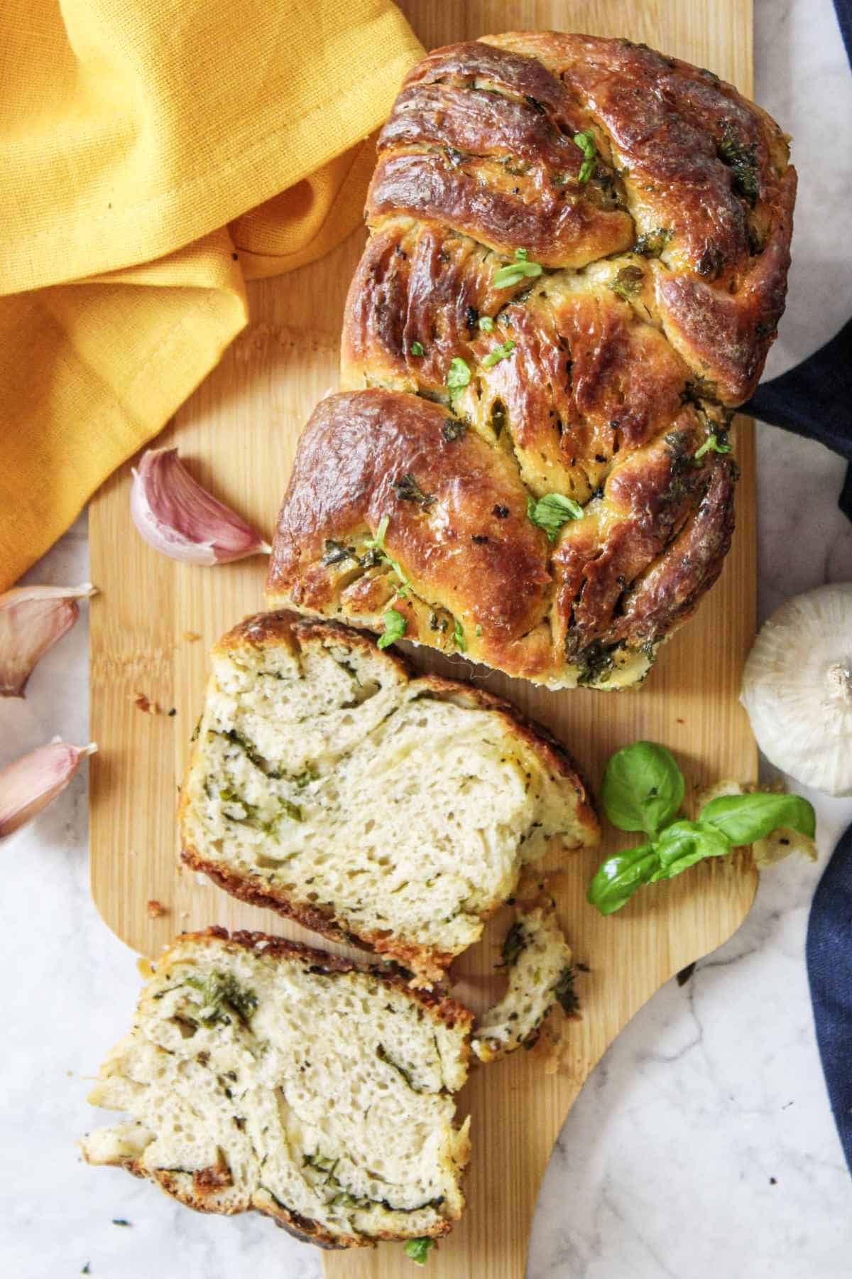 twisted garlic bread on a cutting board with slices spread out.