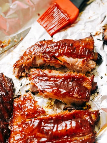 barbeque ribs on white paper with orange basting brush with barbecue sauce on it