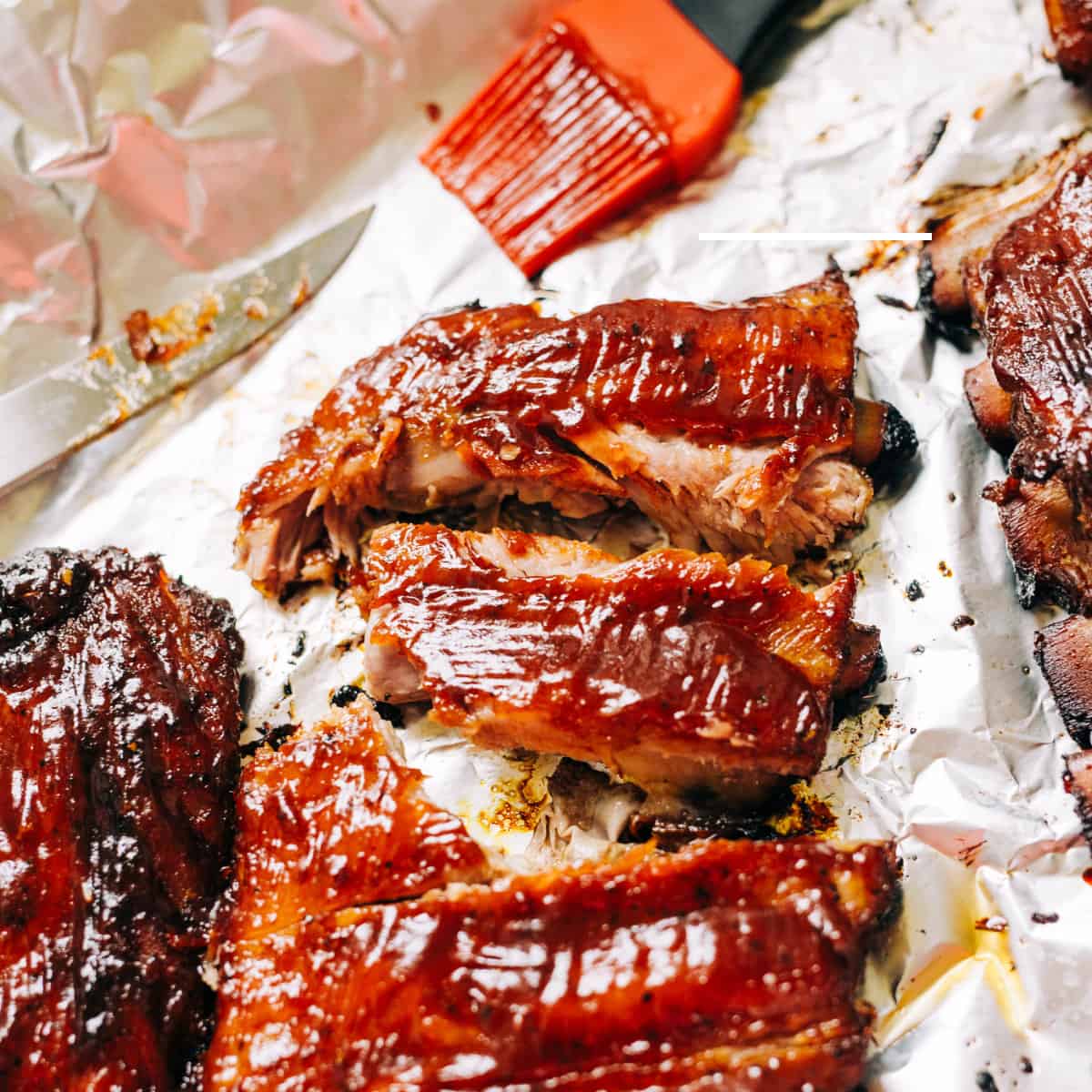 barbeque ribs on white paper with orange basting brush with barbecue sauce on it