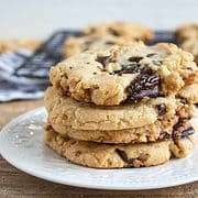 stack of four walnut chocolate chip cookies on a white plate
