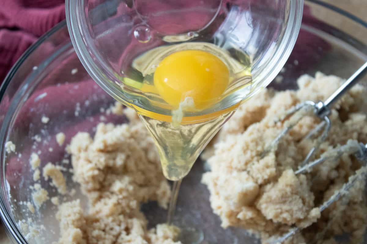 eggs being added to bowl of sugar and butter.