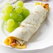 white plate with green grapes and one breakfast flauta