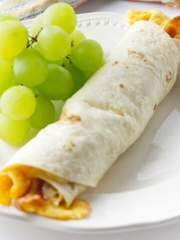 white plate with green grapes and one breakfast flauta