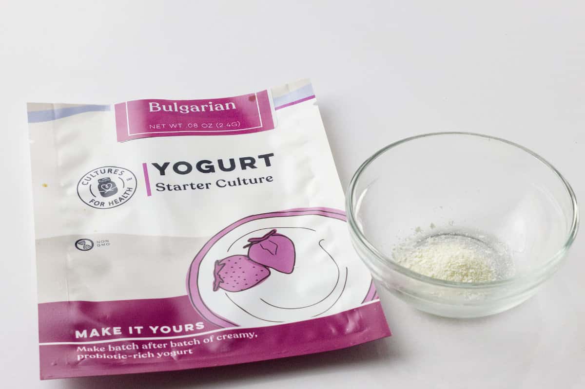 yogurt starter package and powder in a small clear glass bowl