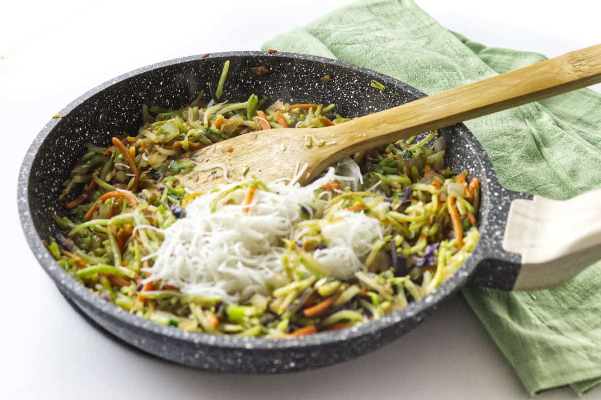 rice noodles added to cooking vegetable mixture in skillet.
