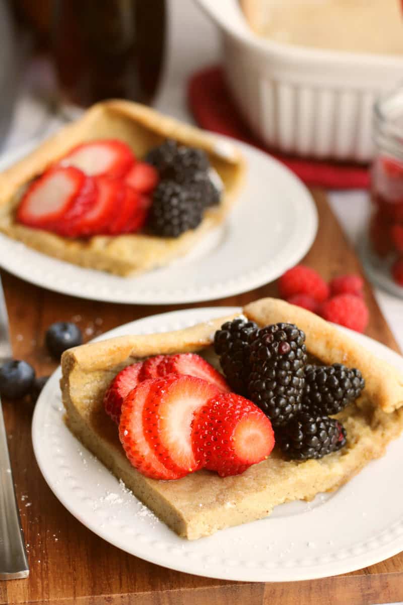 two squares of pancake on white plates, with berries on top.