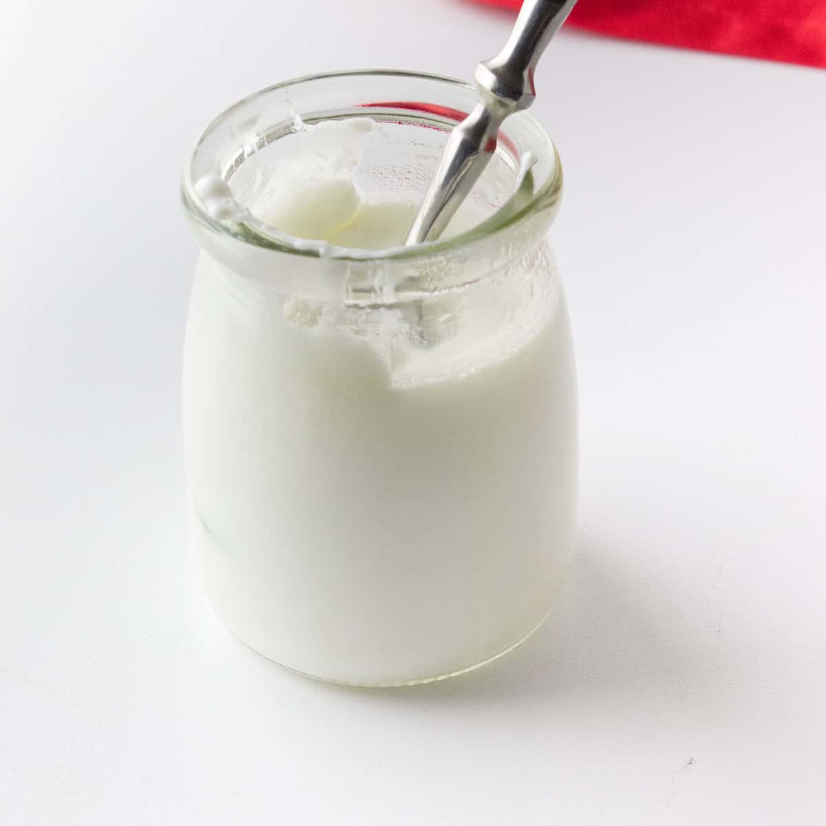 Small jar with some cultured milk and a spoon.