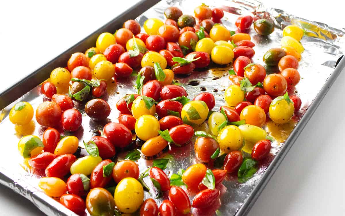 aluminum foil lined baking tray with fresh yellow, orange, green, and red cherry tomatoes.