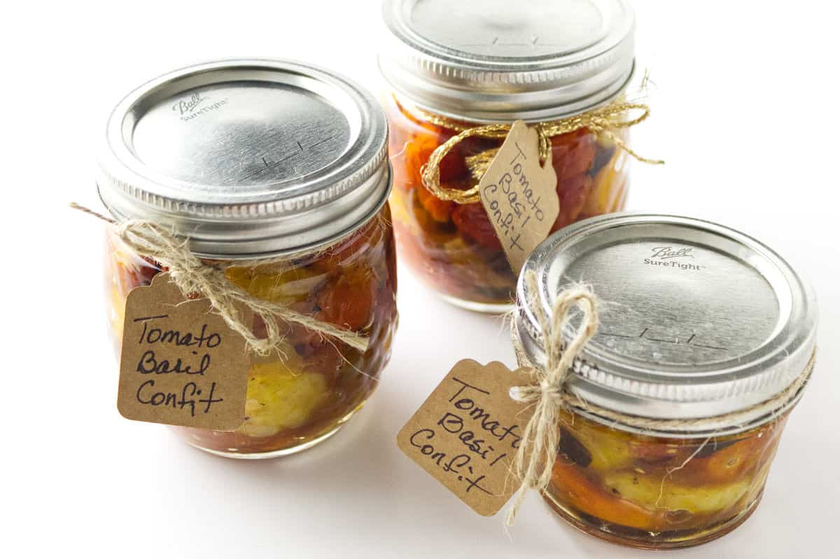 three ball canning jars filled with tomato confit and hang tags for gift giving.