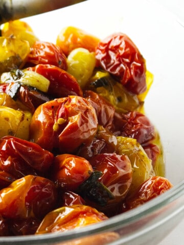clear glass bowl of roasted heirloom cherry tomatoes on a white background