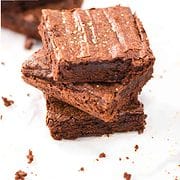 three hershey cocoa brownies stacked on white marble with crumbs nearby