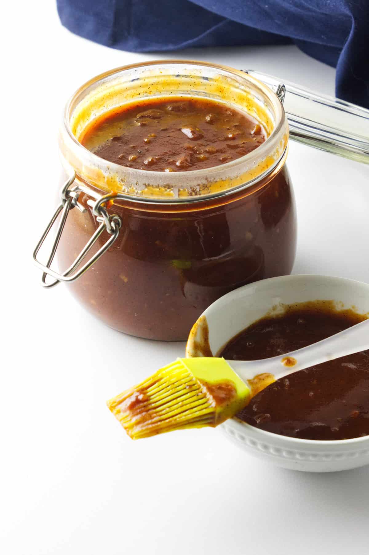 homemade barbeque sauce in a bail jar with basting brush and bowl of sauce.